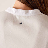 Close-up of a person wearing a white shirt with a small black logo on a light background