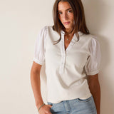 Woman wearing a white blouse and blue jeans against a plain background