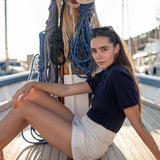 Woman sitting on a boat deck with ropes and nautical equipment in the background