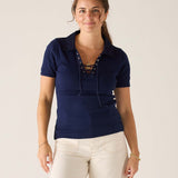 Woman wearing a navy blue polo shirt with lace-up details on a plain background