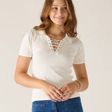 Woman wearing a white lace-up top and blue jeans against a plain background