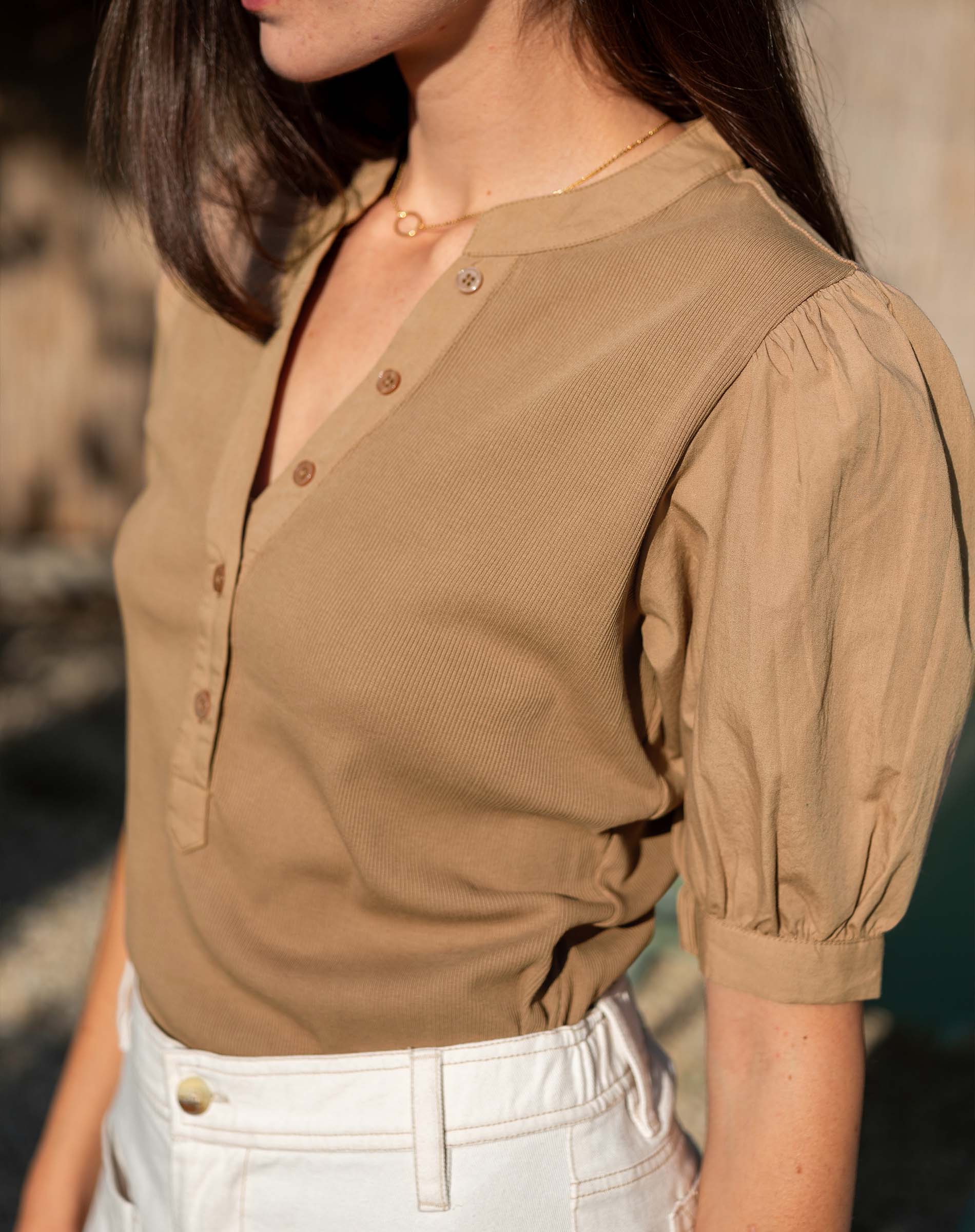 Woman wearing a brown blouse with short sleeves and a blurred background