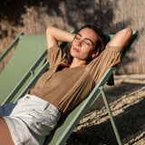Woman relaxing on a green lounge chair outdoors.
