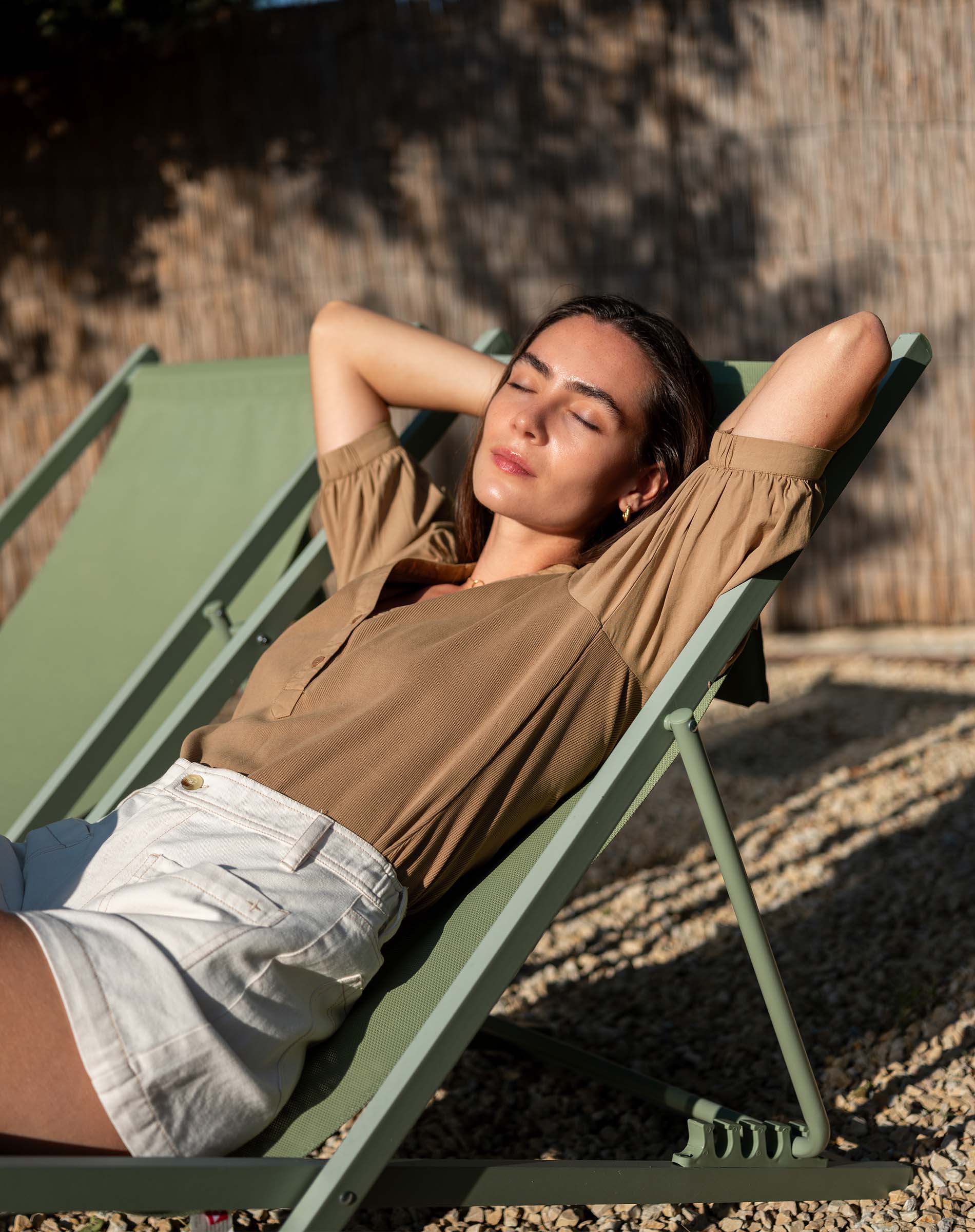 Woman relaxing on a green lounge chair outdoors.