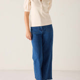 Person wearing a beige blouse and blue jeans on a white background