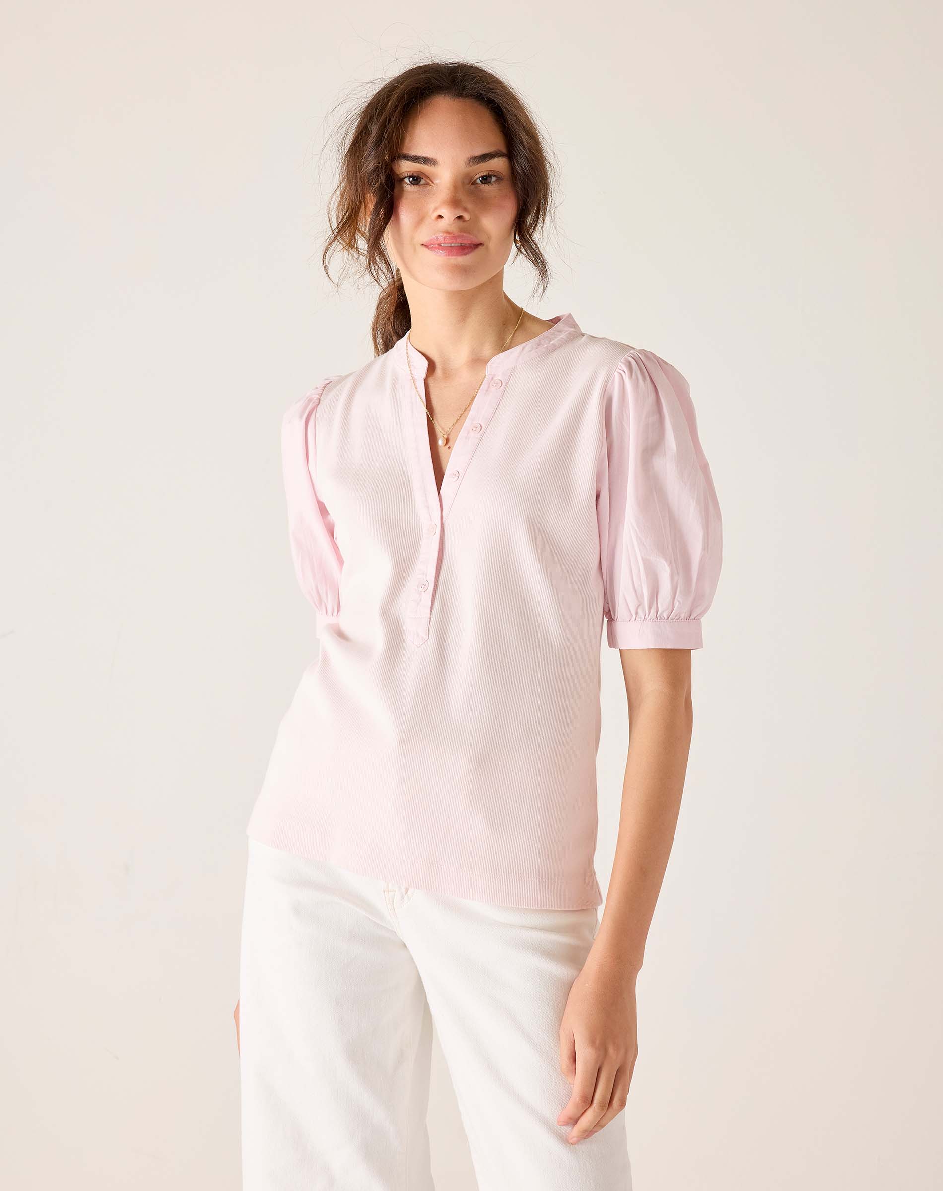 Woman wearing a light pink blouse with puff sleeves against a white background