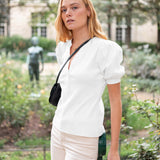 Woman in a white blouse and beige pants standing in a garden