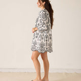 Woman wearing a black and white patterned dress against a plain background