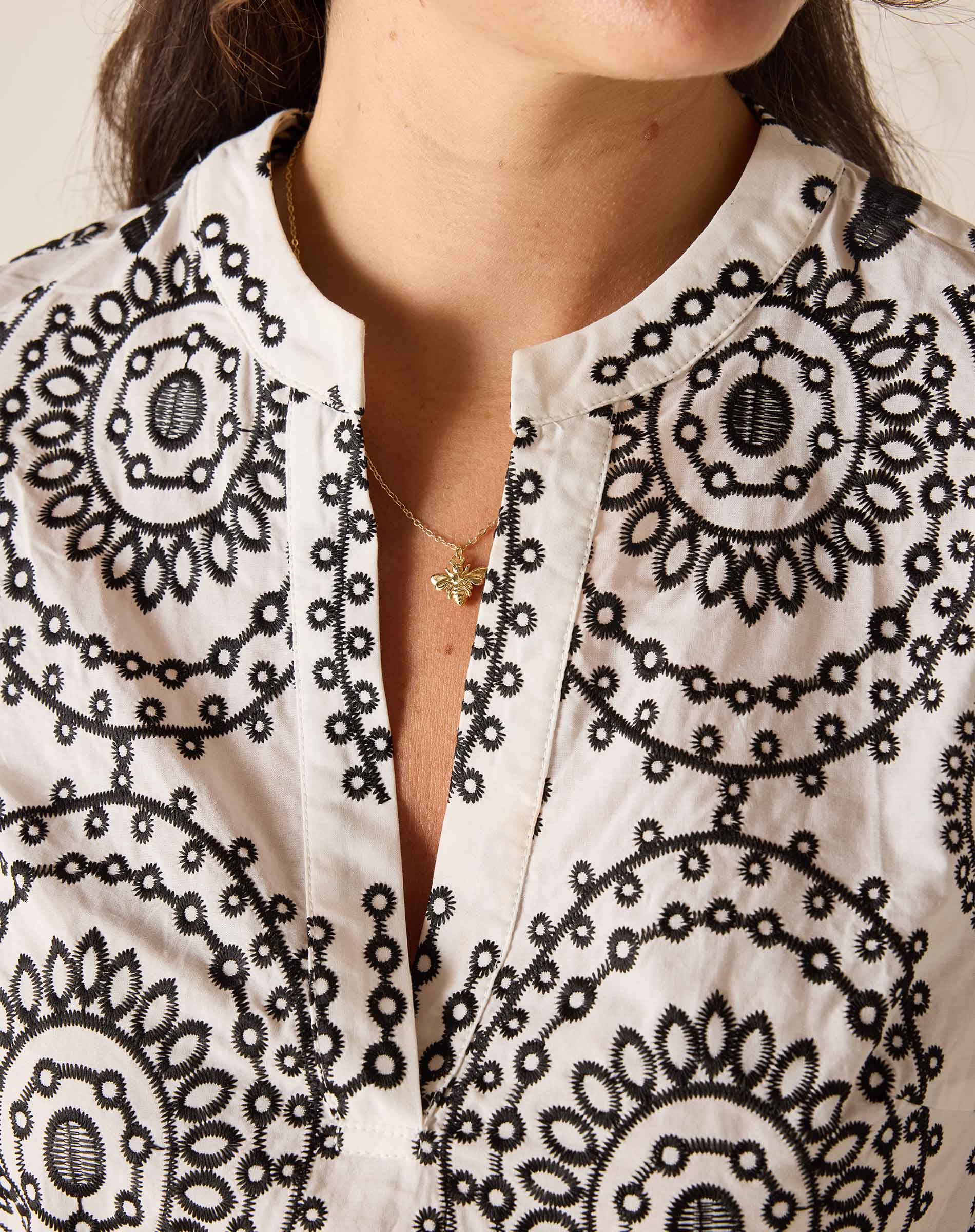 Close-up of a person wearing a white blouse with black circular patterns.