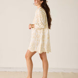 Woman wearing a light-colored floral dress against a plain background