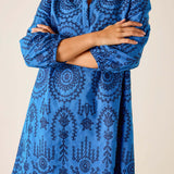 Blue patterned dress worn by a person on a beige background