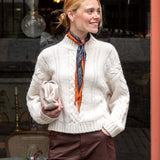 Cream cable knit sweater with a high neckline and textured detailing.