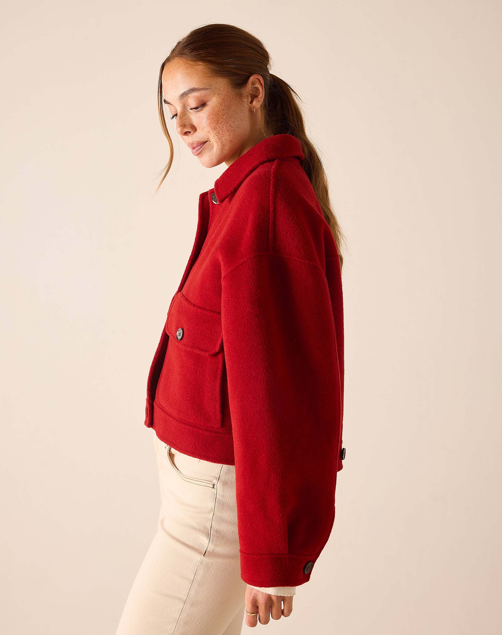 Garnet red wool-blend knit jacket with buttoned front and oversized pockets.