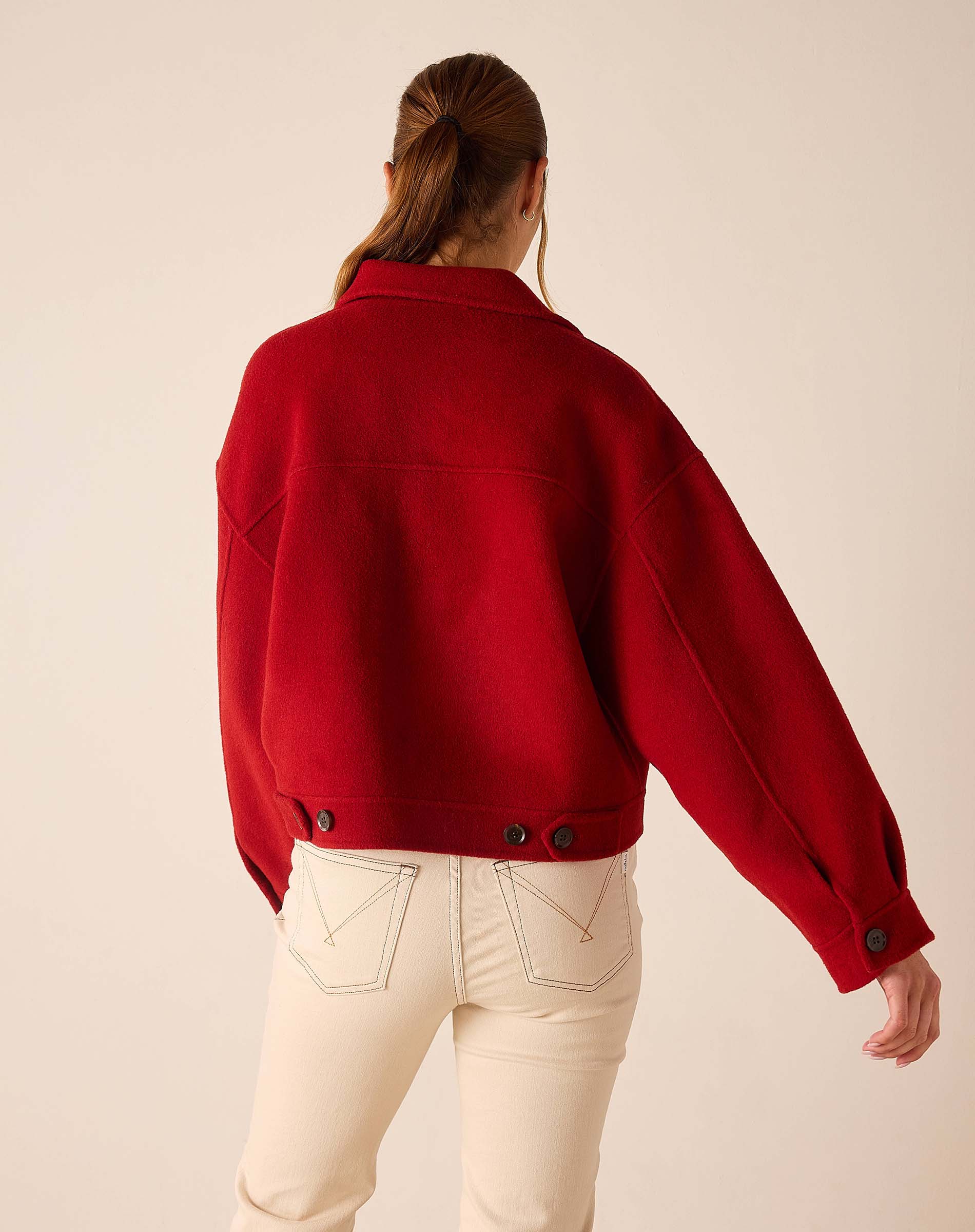 Back view of women's travel-friendly garnet red knit wool-blend jacket with buttoned cuffs and relaxed fit.