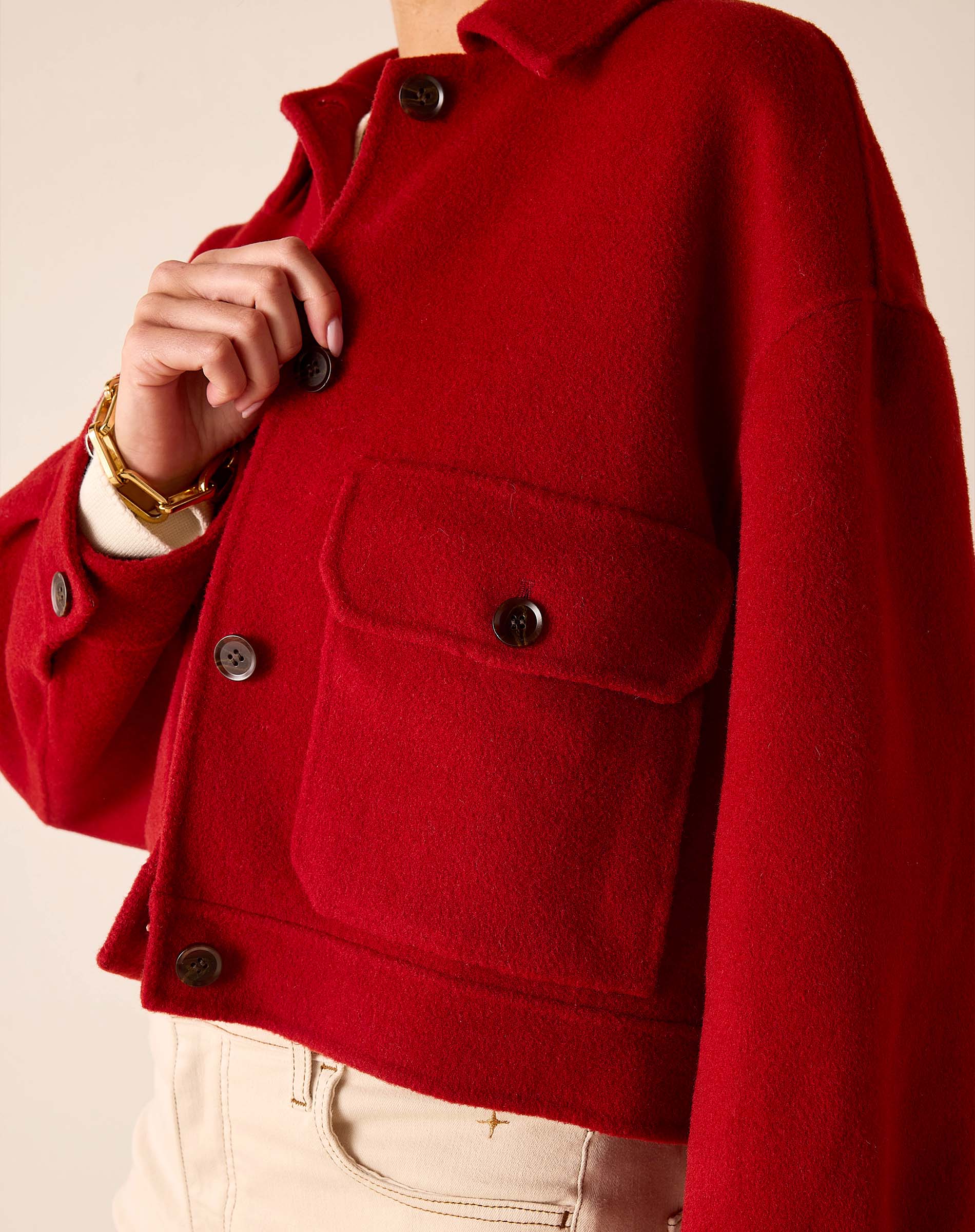 Garnet red knit wool jacket with large patch pockets and button details.