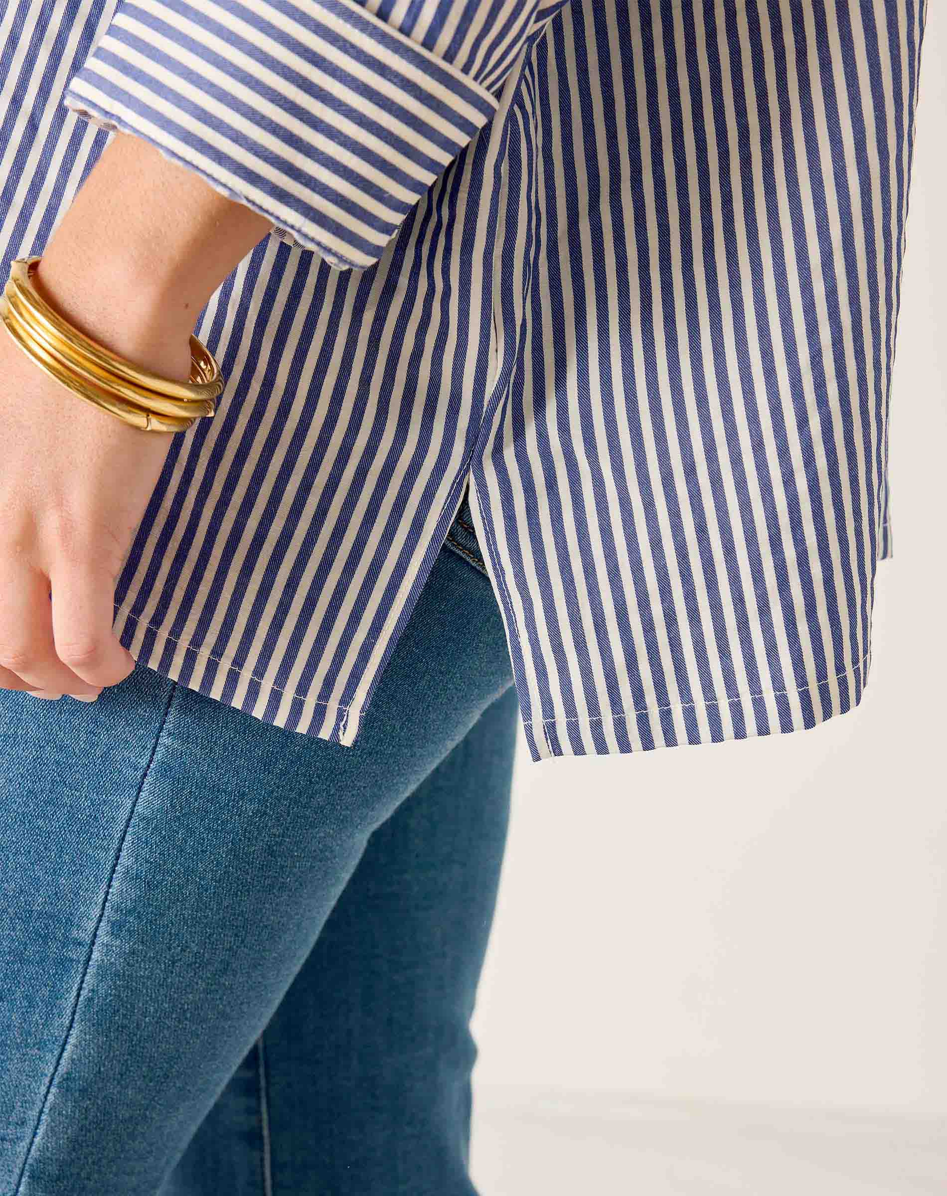Close-up of a person wearing a blue and white striped shirt and blue jeans on a white background