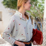 Light blue button-down shirt with red cherry print and a collar, held by model in front of a garden.
