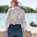 Back view of the light gray button-down shirt with a red cherry print and high-waisted blue denim jeans.