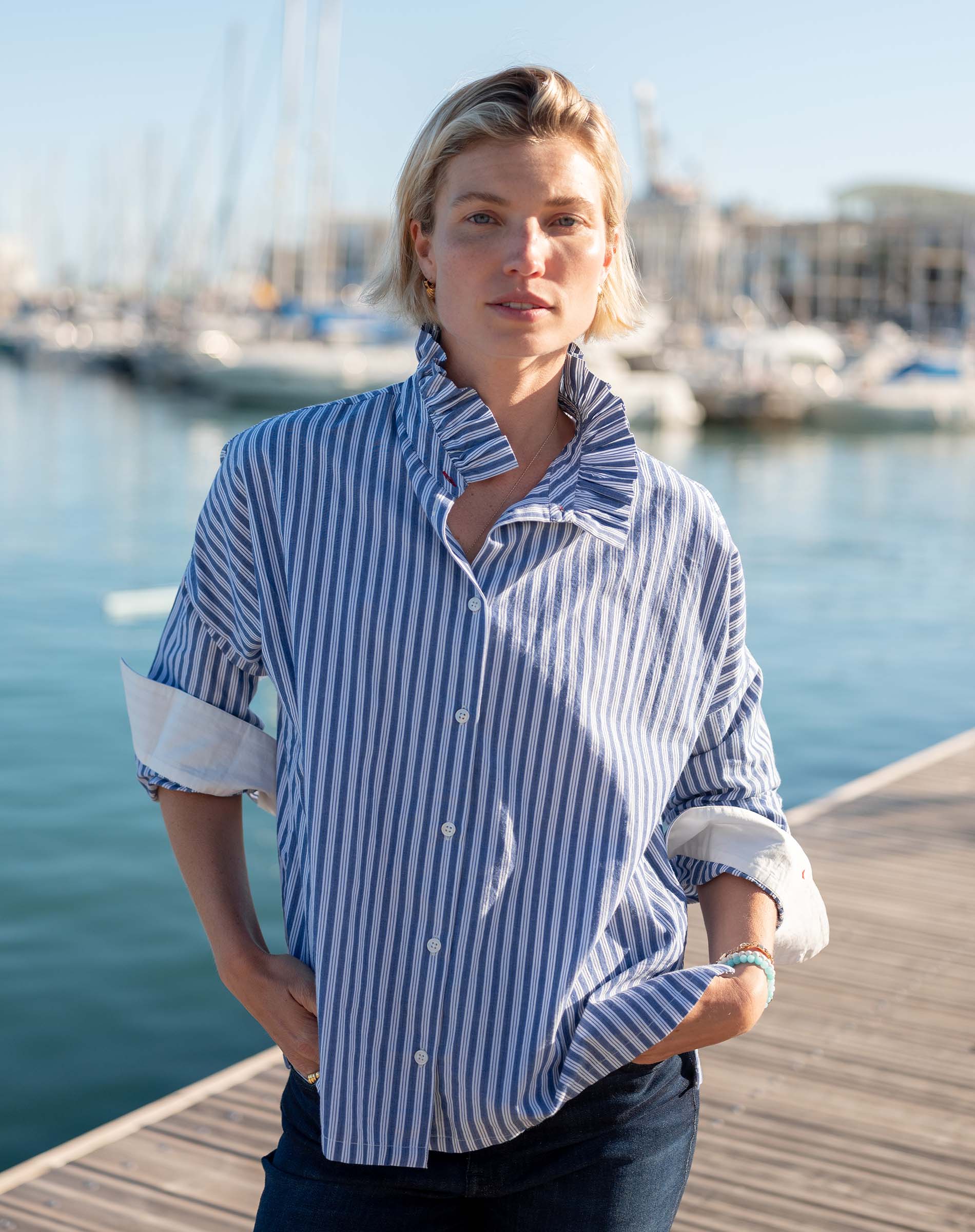 Blue double stripe shirt with an Elizabethan collar and rolled sleeves set in a harbor scene.