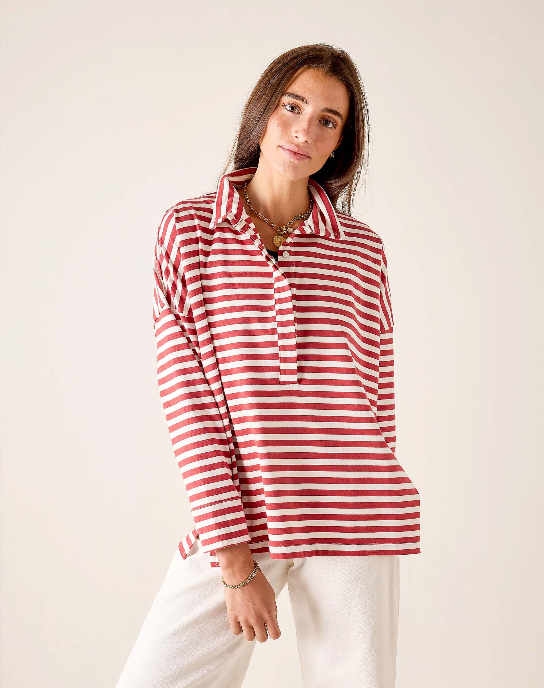 Model wearing an oversized red and white striped pop-up collar knit top with white pants.