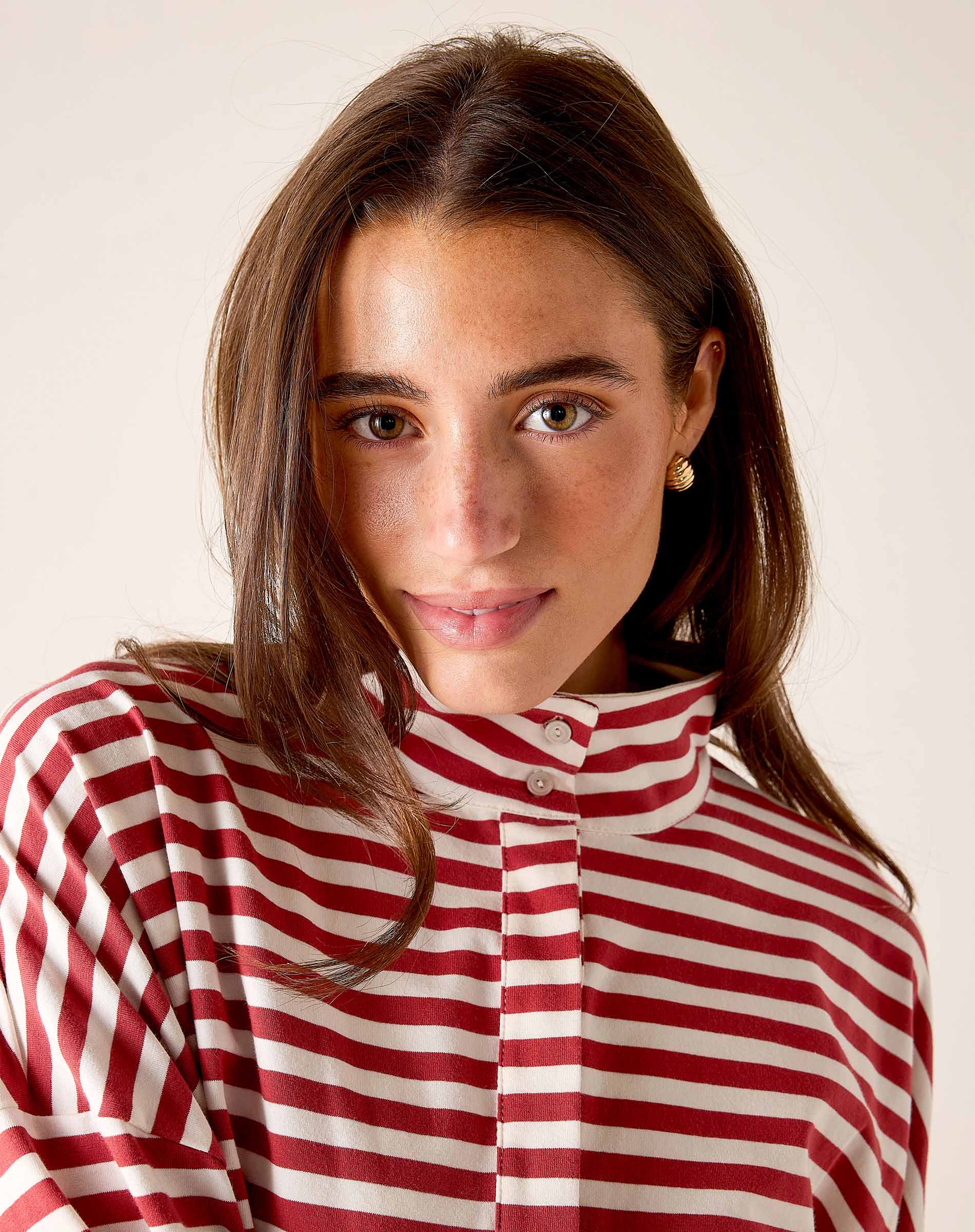Woman wearing a red and white striped shirt against a plain background