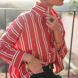 Person wearing a red and white striped shirt with accessories on a blurred outdoor background