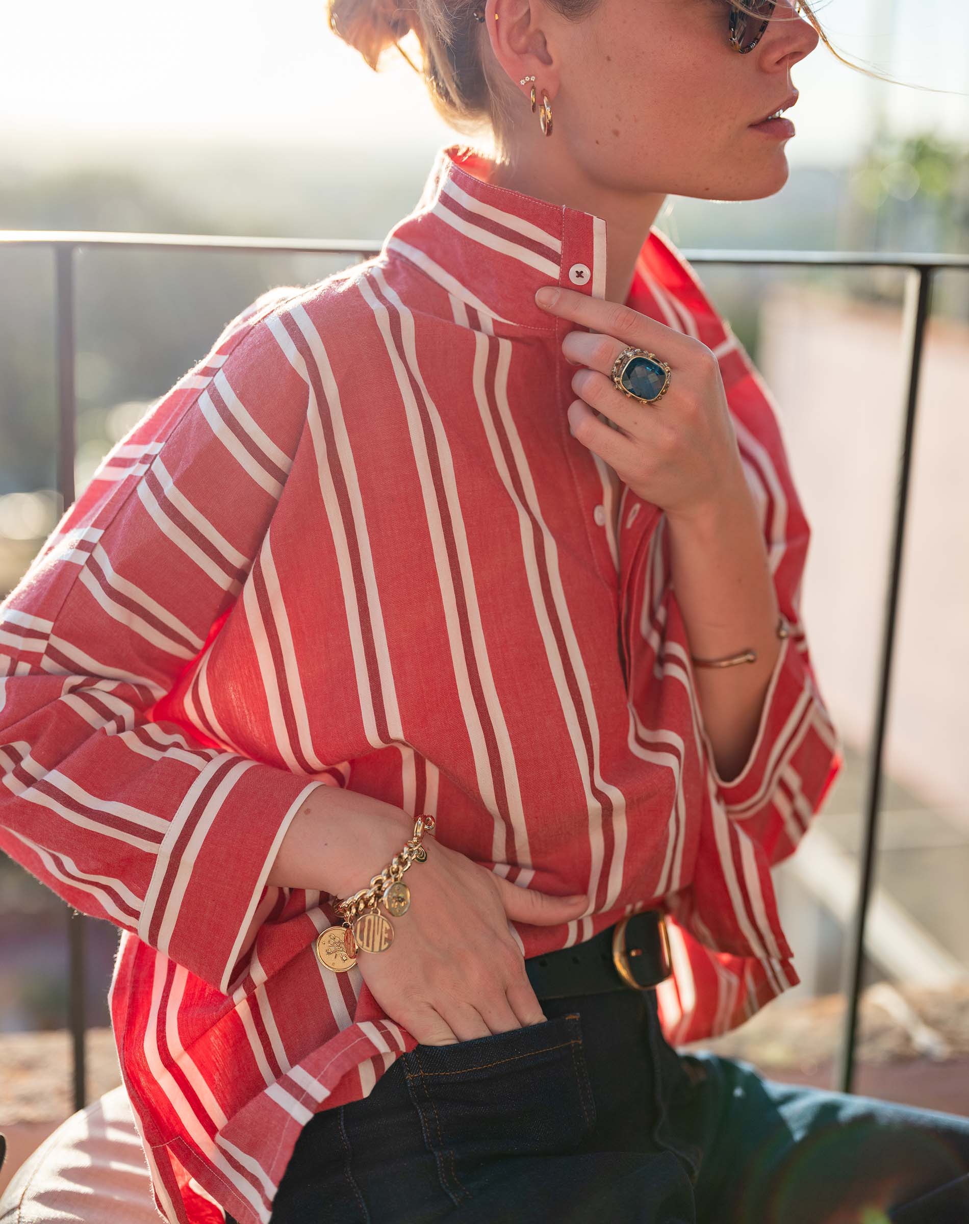 Person wearing a red and white striped shirt with accessories on a blurred outdoor background