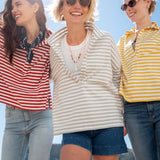 Three women wearing striped shirts on a beach