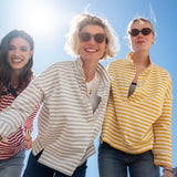 Three women standing together outdoors with a clear blue sky.