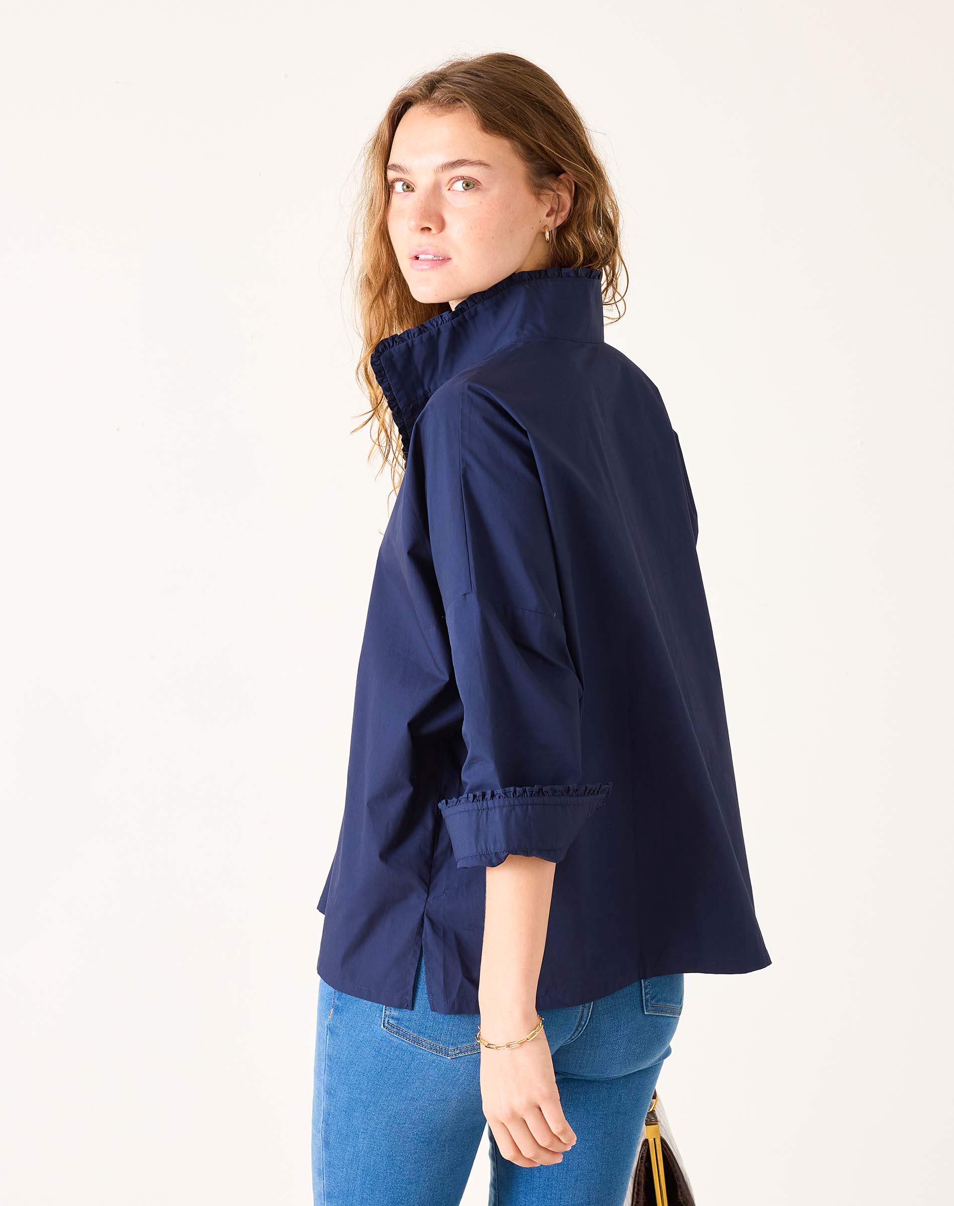 Woman wearing a navy blue jacket and blue jeans on a white background