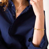 Person wearing a navy blue shirt with gold jewelry on a white background