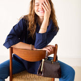Woman sitting on a chair with a handbag next to her, smiling.