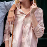 Woman wearing a pink striped shirt with a blurred background