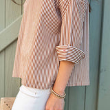 Person wearing a striped shirt and white pants with a neutral background