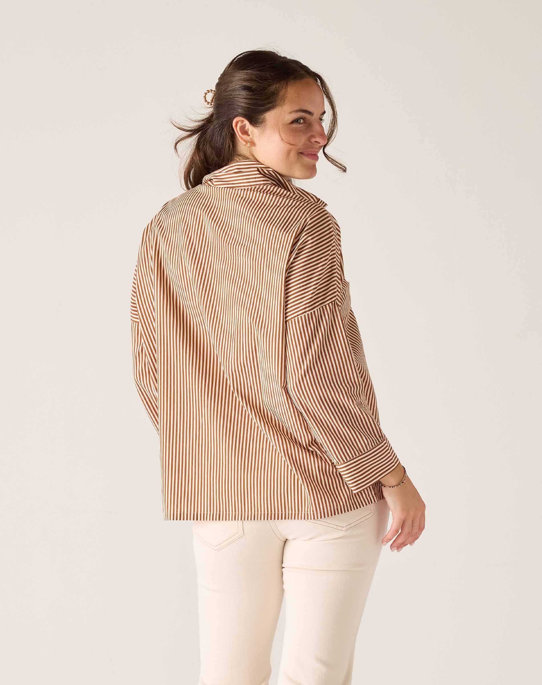 Woman wearing a brown striped shirt against a white background