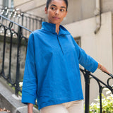 Woman wearing a blue jacket standing on a city street.