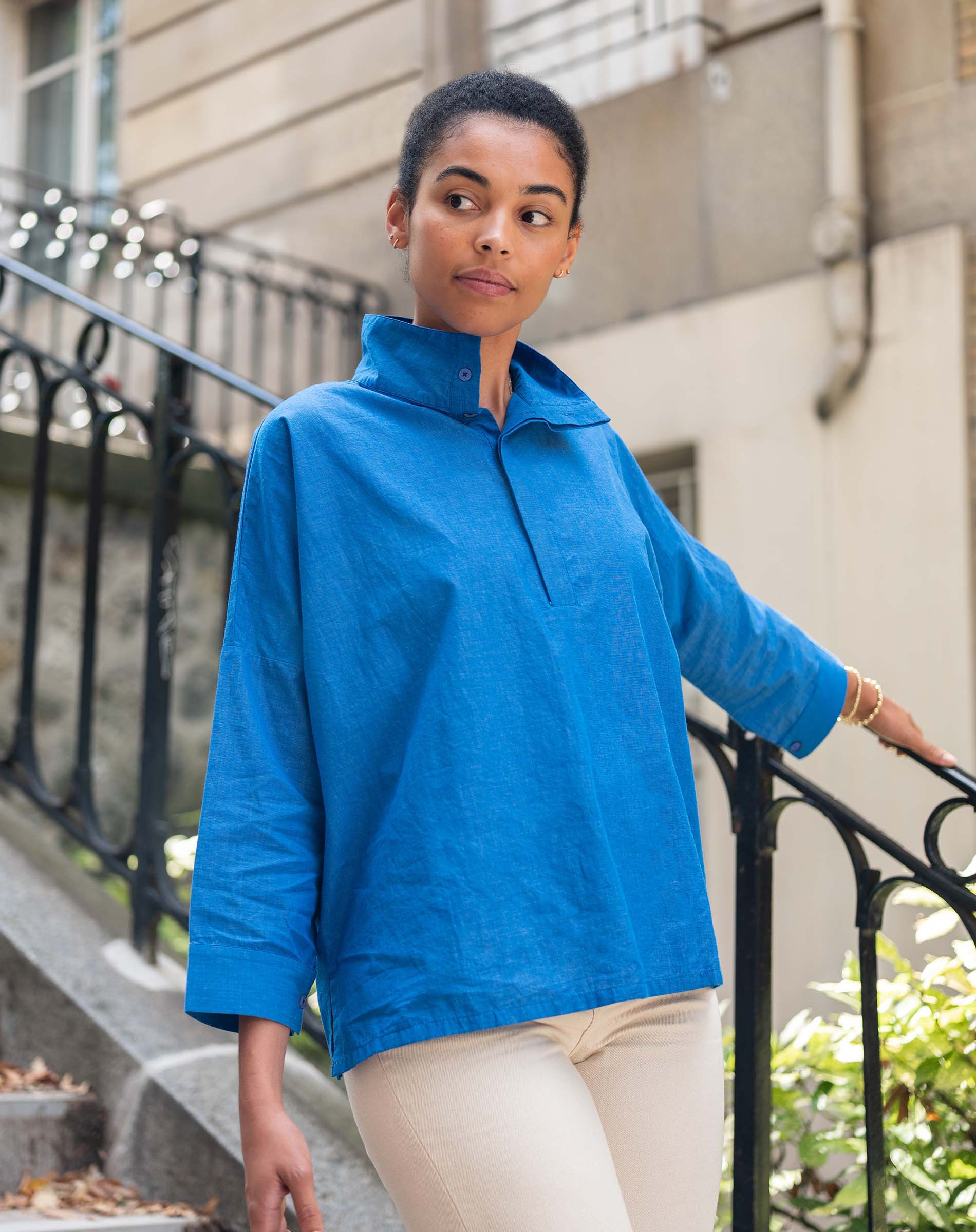 Woman wearing a blue jacket standing on a city street.