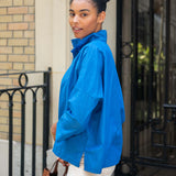 Woman wearing a blue jacket standing outside a building.
