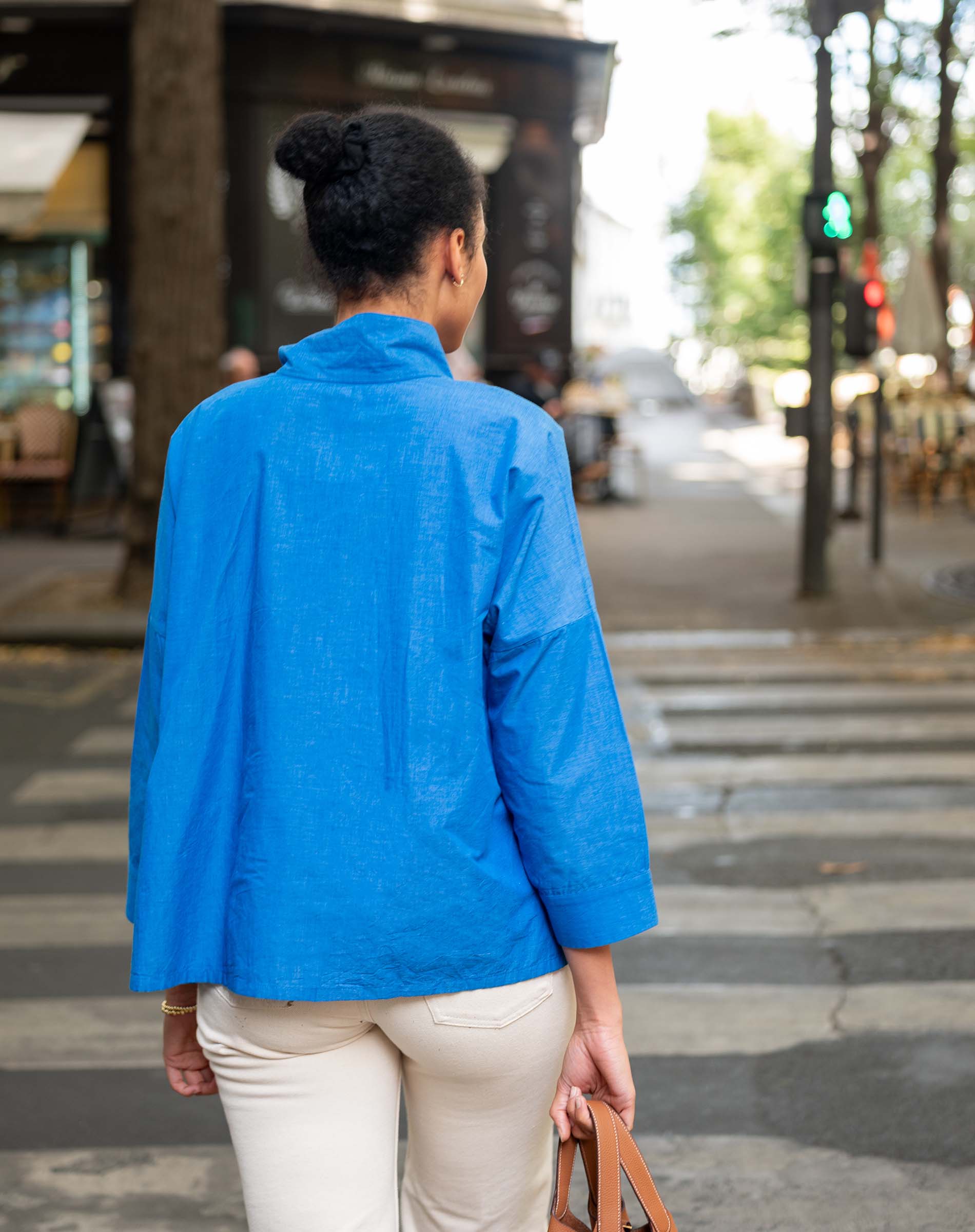Person wearing a blue jacket walking on a city street