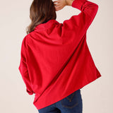 Side view of a cardinal red oversized knit pullover with dropped shoulders.