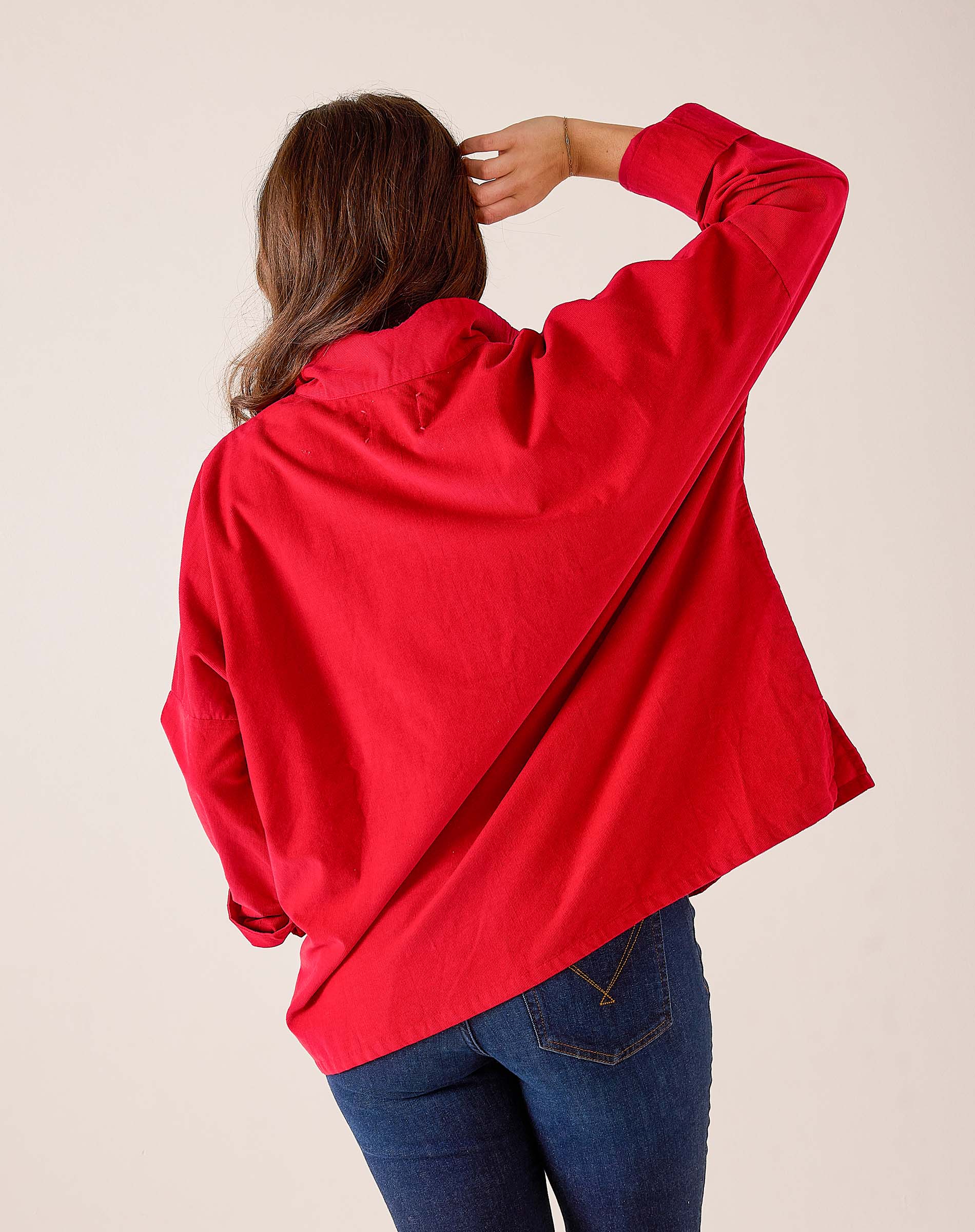 Side view of a cardinal red oversized knit pullover with dropped shoulders.