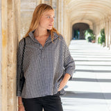 Woman wearing a black and white checkered shirt standing in an architectural setting.