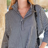 Person wearing a black and white checkered shirt with a blurred background