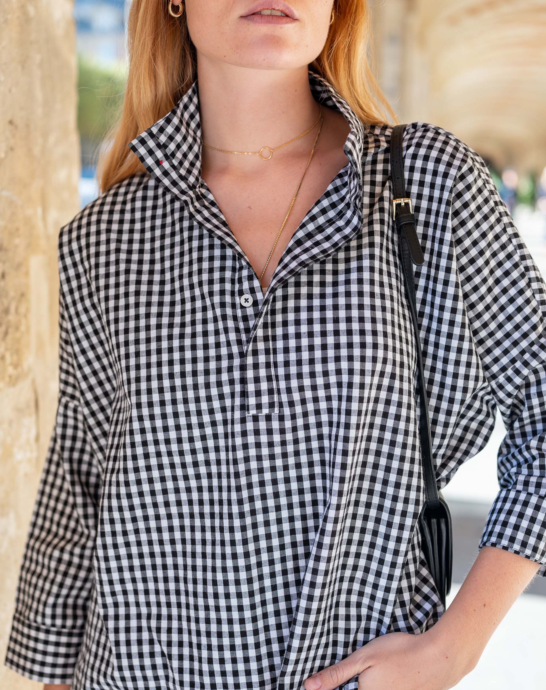 Person wearing a black and white checkered shirt with a blurred background