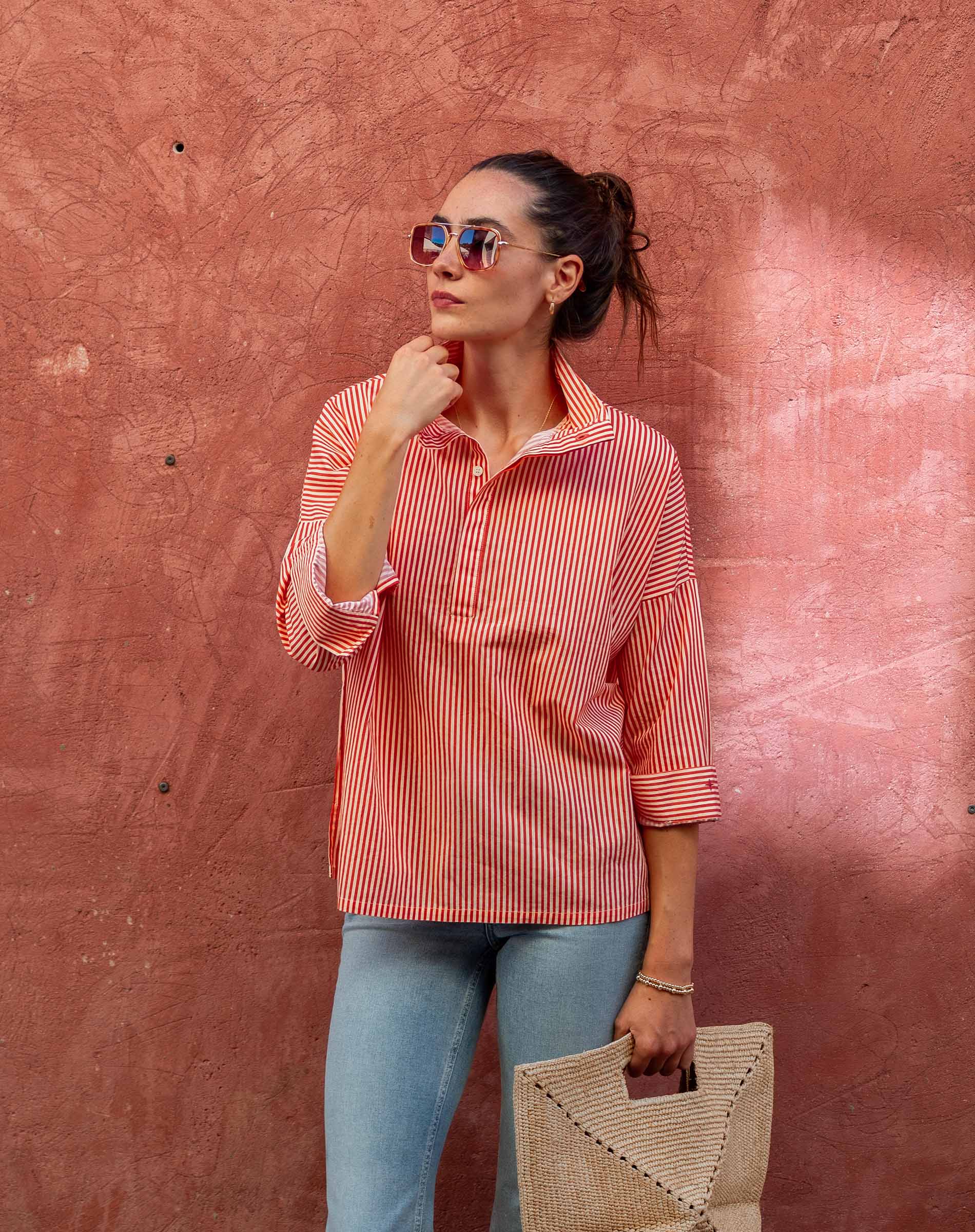 Woman wearing a red and white striped shirt against a textured pink wall