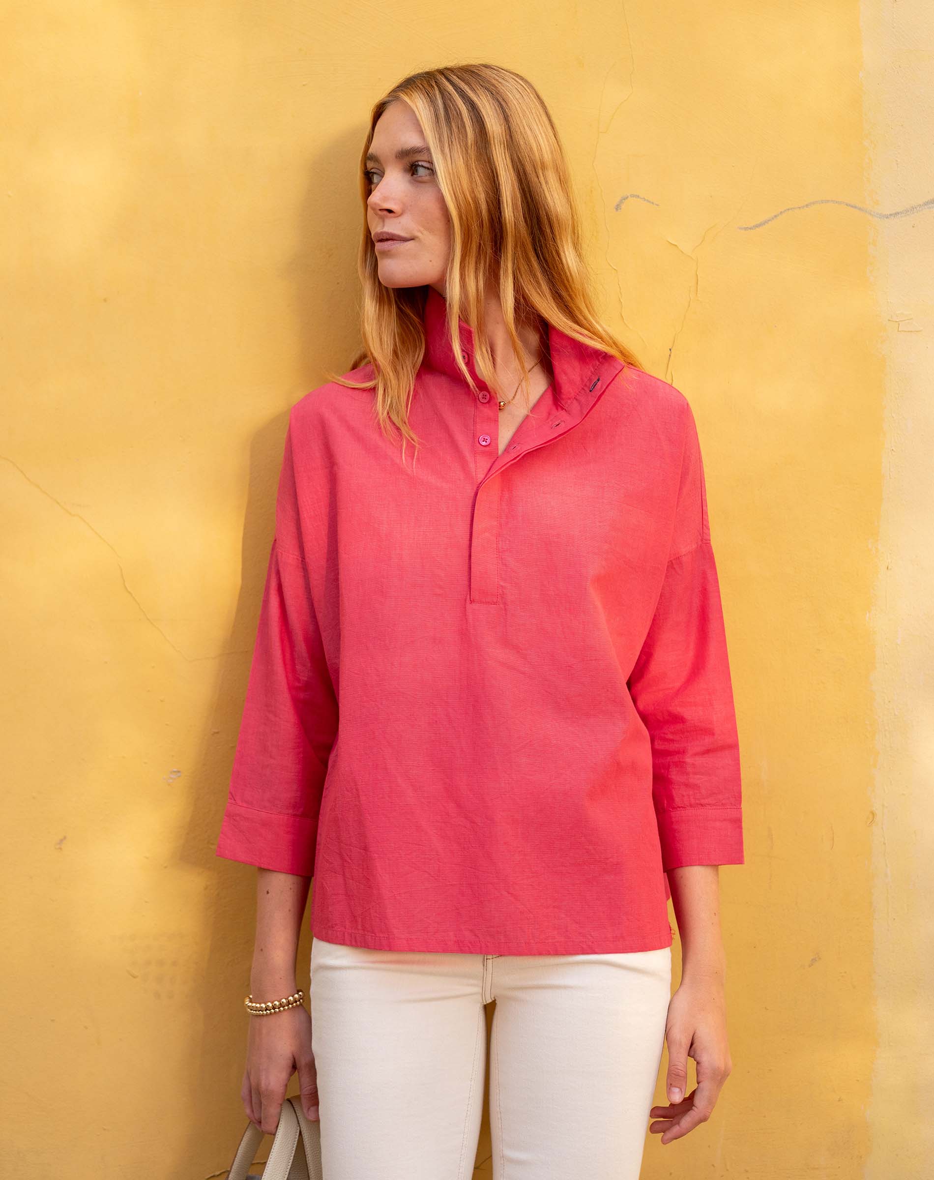 Woman wearing a pink shirt against a yellow wall