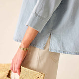 Person wearing a light blue shirt holding a woven bag on a beige background