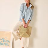 Woman holding a woven bag against a plain background