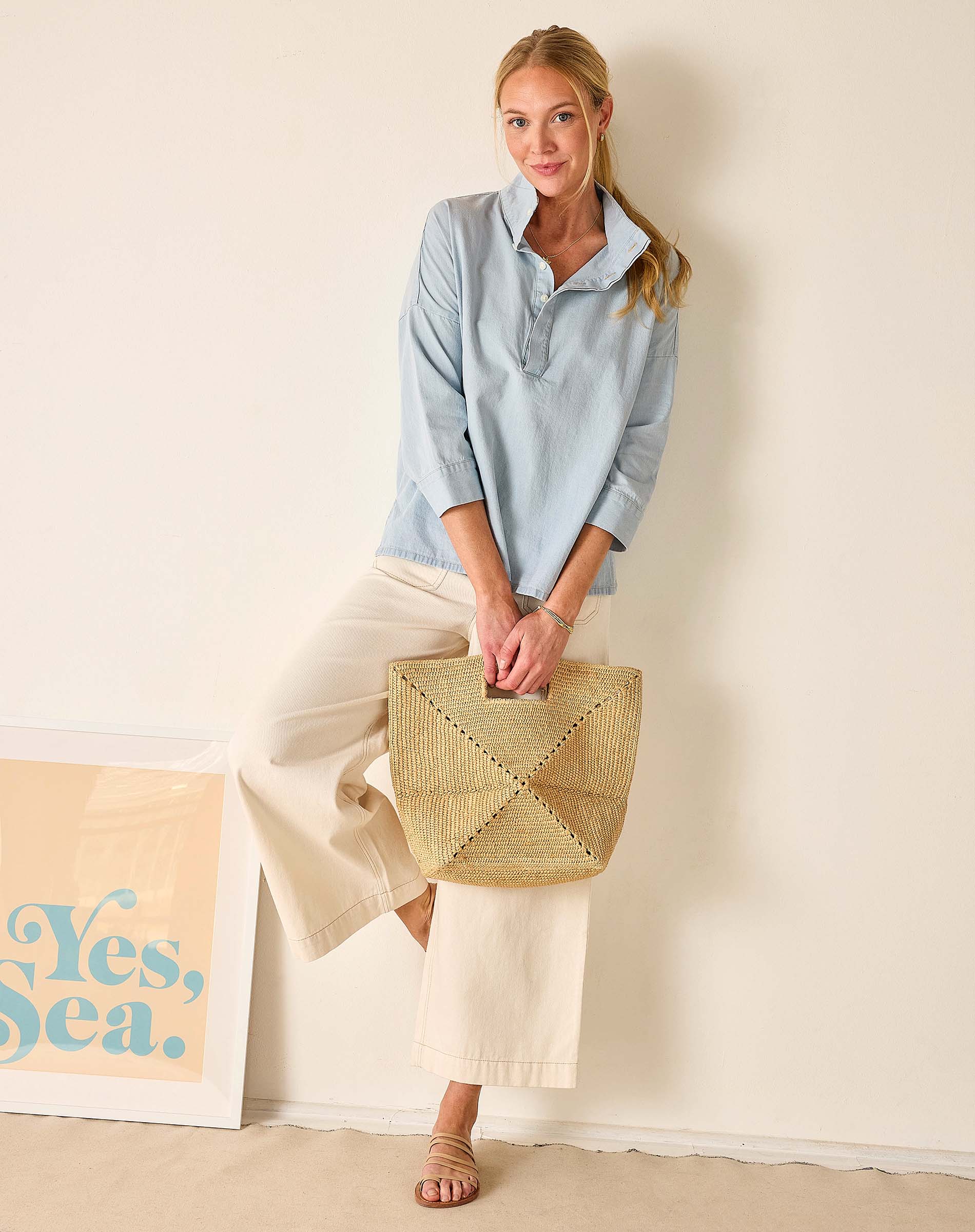 Woman holding a woven bag against a plain background