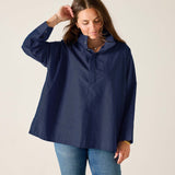 Woman wearing a navy raincoat against a plain background
